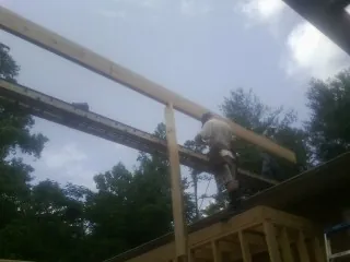 Carpenter setting a ridge beam over a new addition frame — Ice Dam Removal by Roofing Brothers in Gulf Breeze
