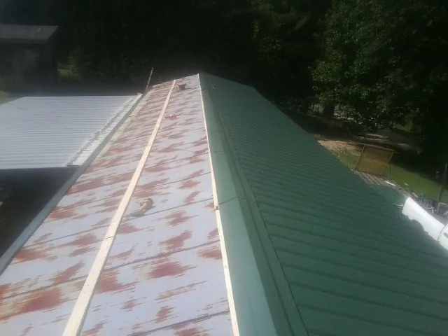 Old rusted panels beside newly installed green metal roofing — Wind Damage Roof Repair by Roofing Brothers in Gulf Breeze