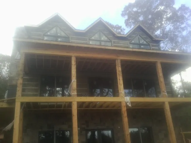 Dormers and porch framing on a large log home under construction — Roof Coating work by our crew in Gulf Breeze