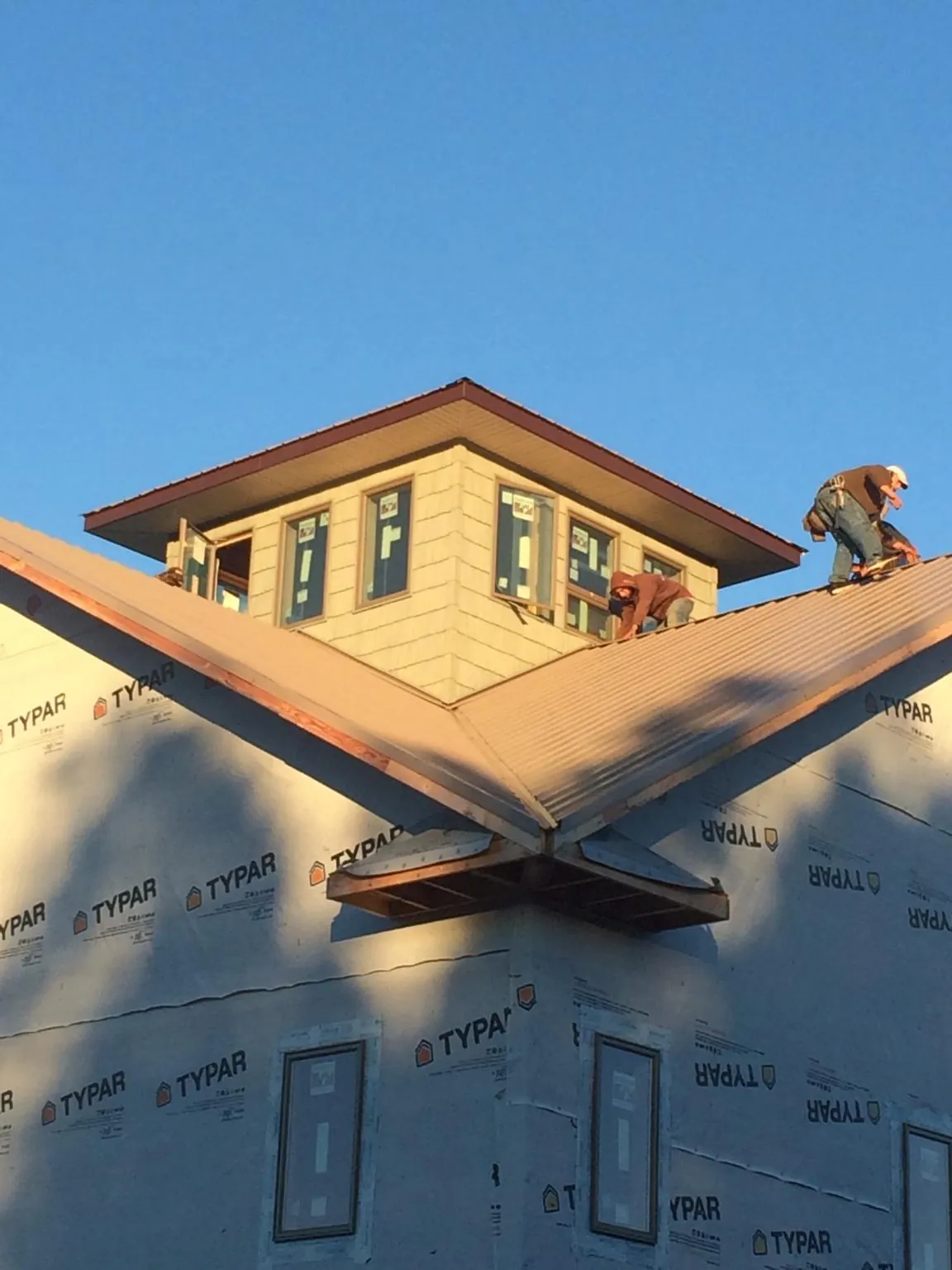 Roofers working around a rooftop cupola on a new metal roof at sunset — Roof Waterproofing in Gulf Breeze by Roofing Brothers